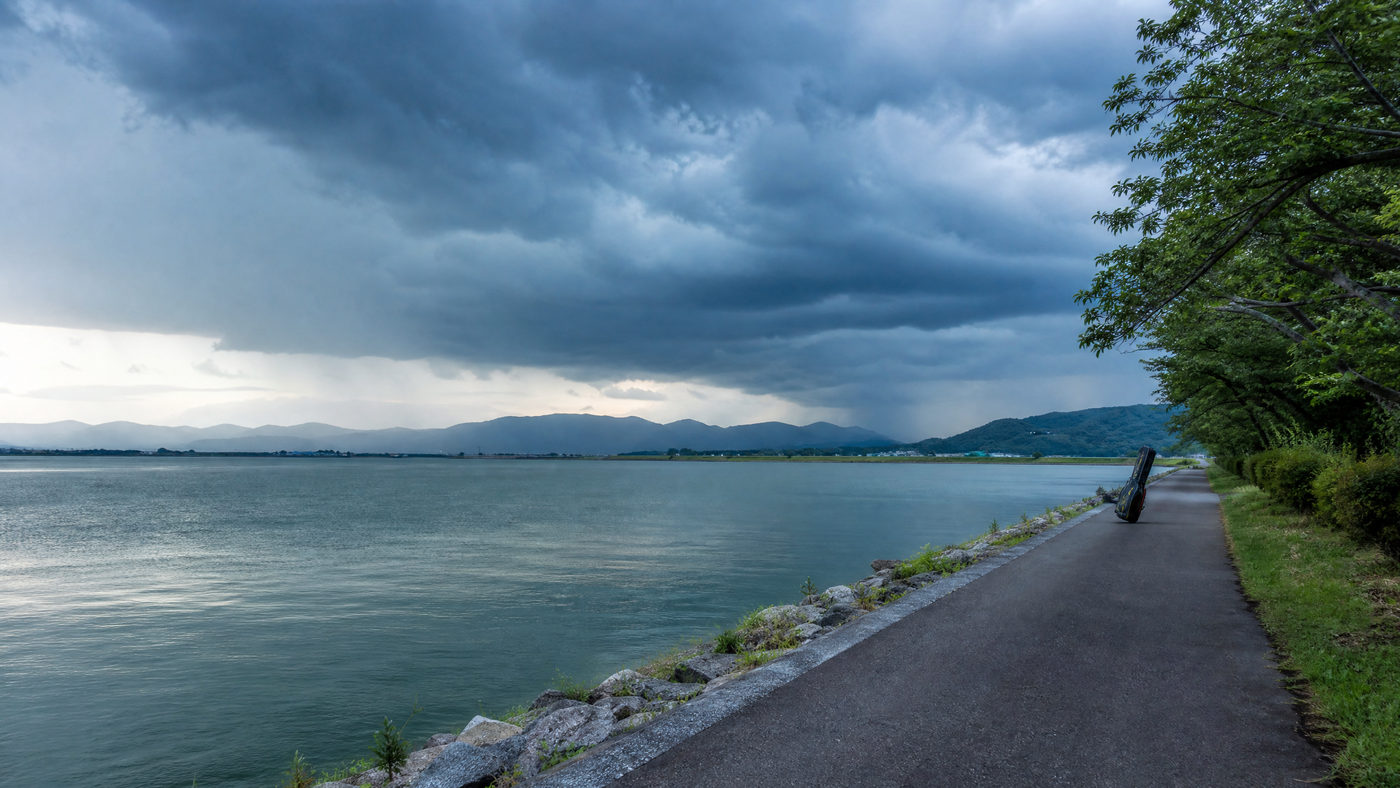 遠くに雷雲が発達するなか、空いた安全な湖岸を写した写真